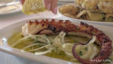 用柠檬汁浇炸章鱼的特写镜头，然后吃，餐厅里的海鲜配上酱汁和